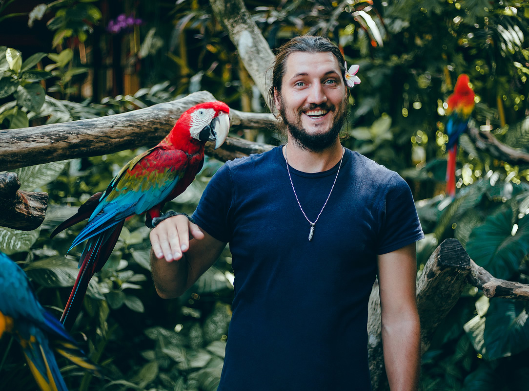 Young guy posing zoo with parrot